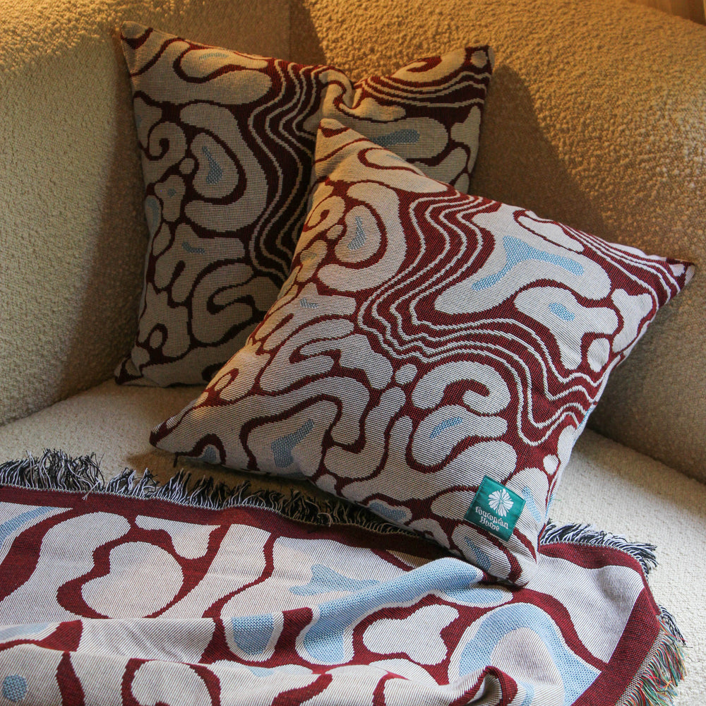 Patterned cushions and blanket on a beige sofa