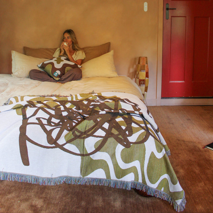 Woman lying on a bed with a colorful blanket in a room with a red door.