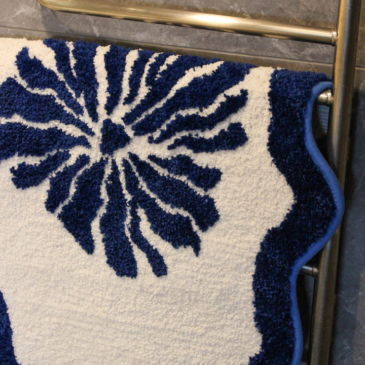 Navy blue and white patterned bath mat on a metal towel rack